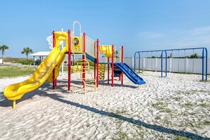 Ein Spielplatz mit zwei Rutschen und einer Kletterkonstruktion auf Sandboden.