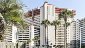 Een hoog hotel met meerdere balkons en palmbomen.