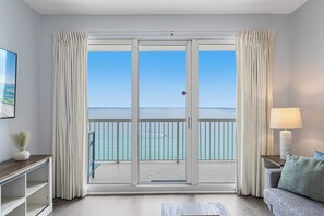 Une pièce dotée d’une porte-fenêtre coulissante donnant sur un balcon avec vue sur la mer.