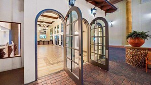 Un vestíbulo interior con suelo de madera, una planta grande en maceta y una recepción con mostrador.
