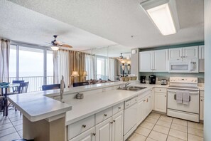 A modern kitchen with white cabinets, a large island, a microwave, and an oven. - 7th-floor Gulf-front beach-view condo with balcony, on-site pools, hot tub, gym (Panama City Beach)