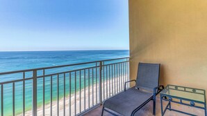 Een balkon met uitzicht op de oceaan, een stoel en een tafeltje.