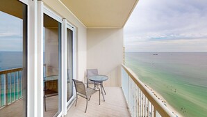 A balcony with a view of the sea, a table, and two chairs. - Beachfront 20th-floor condo with heated pools, hot tubs, balcony & Gulf views (Panama City Beach)
