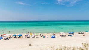 Una playa con agua turquesa cristalina, sombrillas y sillas.