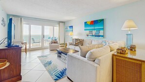 Ein geräumiges Wohnzimmer mit großem Fenster, einem Sofa, einem Couchtisch und einem Fernseher.