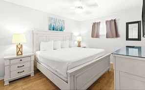 A bedroom with a bed, bedside tables, a dresser, a ceiling fan, a painting, and curtains. - Stunning third-floor condo with balcony, washer&dryer & pool (Destin)