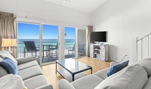 A hotel room with a balcony, a sofa, a coffee table, and a TV. - Stunning third-floor condo with balcony, washer&dryer & pool (Destin)