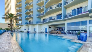 A swimming pool with a clear blue water, surrounded by a tiled deck. - Gulf-front condo with balcony, beach access, hot tub, pool & gym (Panama City Beach)