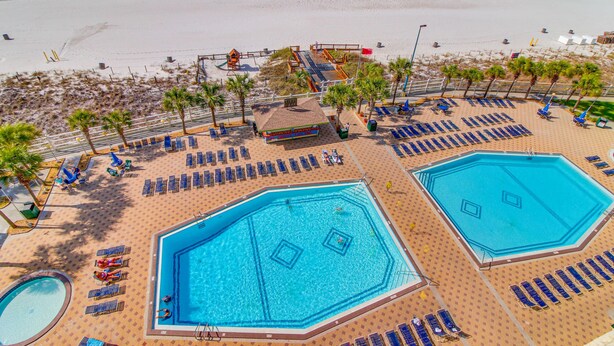 Ein Resort mit mehreren Swimmingpools, Liegestühlen und einem Strandbereich.