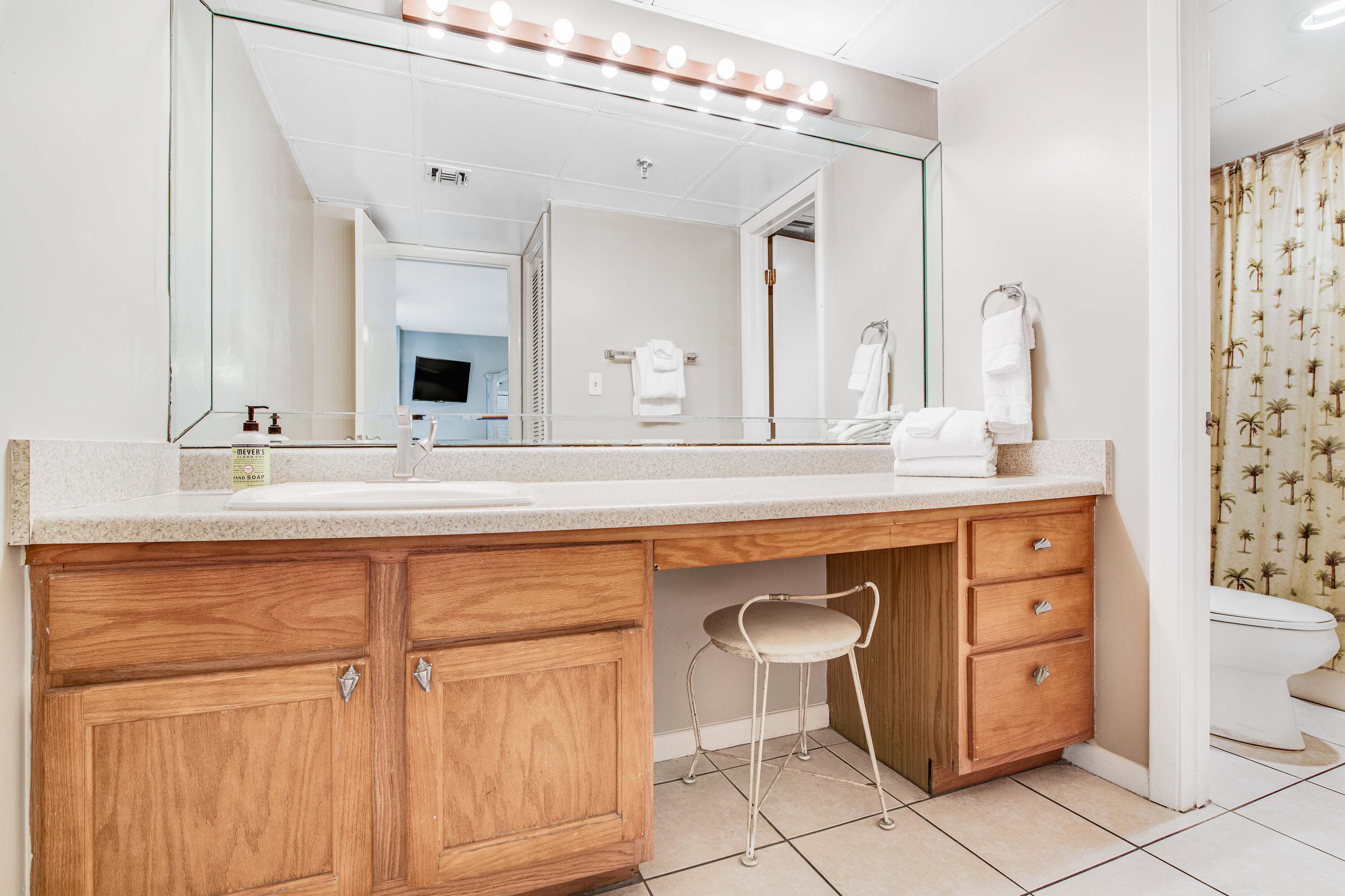 A bathroom with a vanity, mirror, and toilet.