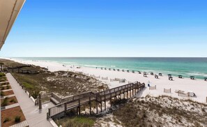 A beach with a wooden boardwalk, beach chairs, and umbrellas. - Wonderful Gulf-front condo with pool & beach boardwalk in the heart of Destin (Destin)