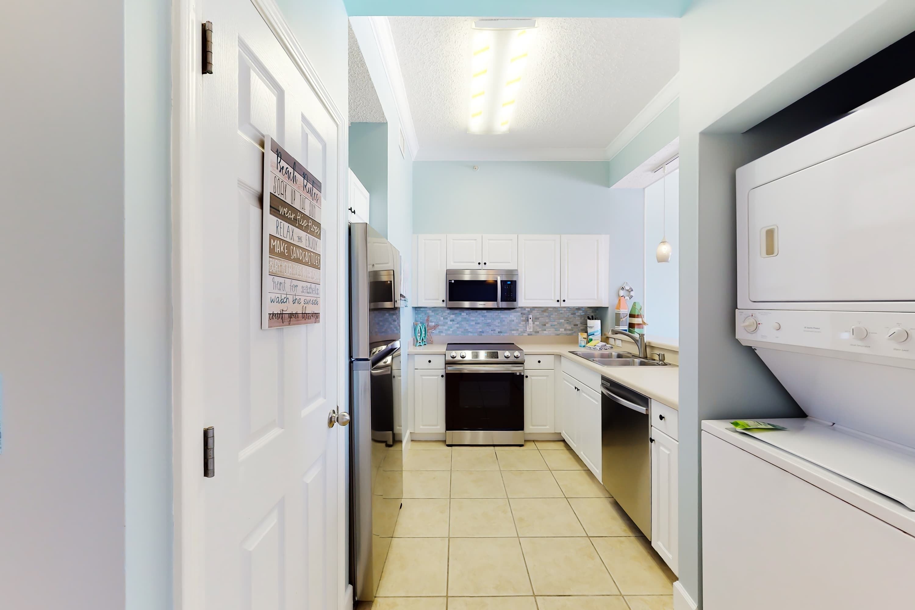 A compact kitchen with white cabinets, a stainless steel oven, a microwave, and a dishwasher.