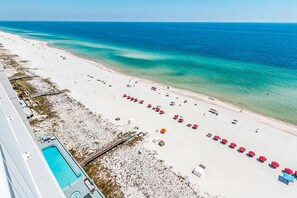 Uma praia com piscina, guarda-sóis e espreguiçadeiras.