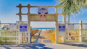 A beach entrance with signs indicating no lifeguard, swimming at own risk, and no glass containers on the beach. - Gulf-front condo with balcony, W/D, direct beach access, pools, hot tub & gym (Panama City Beach)