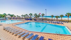 A pool area with two pools, lounge chairs, palm trees, and a beach view. - Gulf-front condo with balcony, W/D, direct beach access, pools, hot tub & gym (Panama City Beach)
