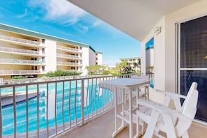 A balcony with a view of a swimming pool and adjacent buildings. - Lovely condo with pool, hot tub, ocean views & pickleball (Santa Rosa Beach)