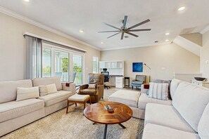 A spacious living room with a high ceiling fan, a large window, and a view of the outdoors.
