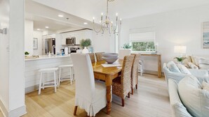 Una cocina moderna con armarios blancos, una mesa de comedor de madera y una araña.