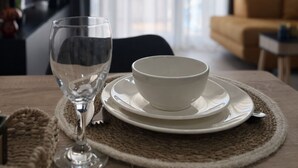 Een eettafel met een glas, kom en schotel in een moderne kamer met uitzicht op de stad door grote ramen.