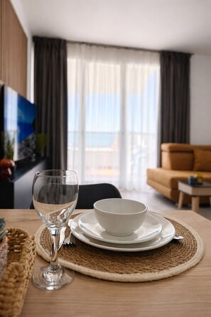 Una mesa de comedor con una copa, un tazón y platos sobre un posavasos tejido.