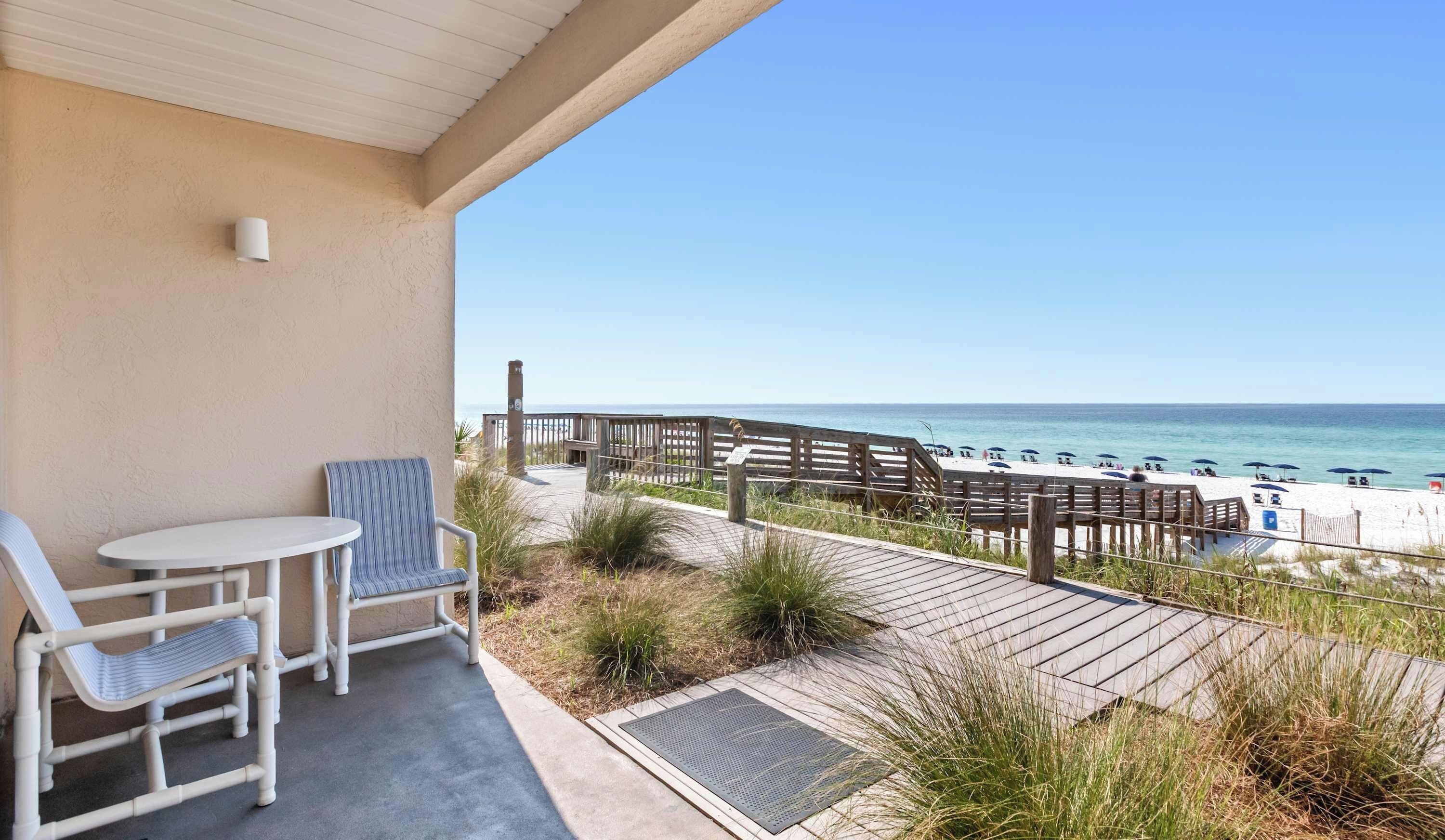Un balcon avec vue sur la plage, comprenant une terrasse en bois et des parasols de plage.