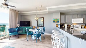 Ein modernes Wohnzimmer mit Sofa, Esstisch und Stühlen, eine Küche mit Mikrowelle und Schränken sowie ein Balkon mit Blick.