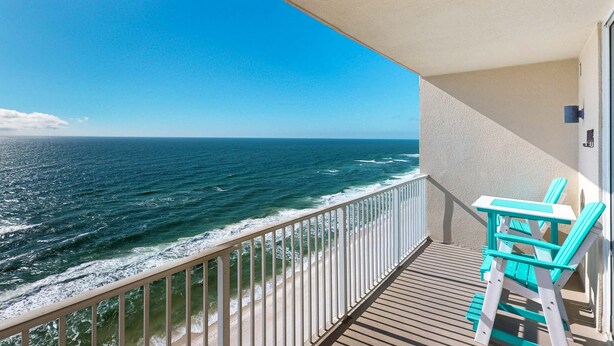 Ein Balkon mit Blick auf das Meer, eine Holzterrasse und zwei türkisfarbene Stühle.