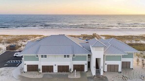 A coastal building with a garage and a covered parking area, adjacent to a beach. - Golf getaway near the beach with shared pool, balcony, & WiFi - gorgeous view (Perdido Key)