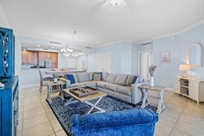 A spacious living room with a sectional sofa, a coffee table, and a dining area with a kitchen in the background. - Golf getaway near the beach with shared pool, balcony, & WiFi - gorgeous view (Perdido Key)