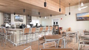 A modern restaurant with wooden ceiling, metal chairs, and tables. There are bar counters with bottles and a television screen. - Golf getaway near the beach with shared pool, balcony, & WiFi - gorgeous view (Perdido Key)