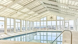 An indoor swimming pool with clear glass walls and a high ceiling.