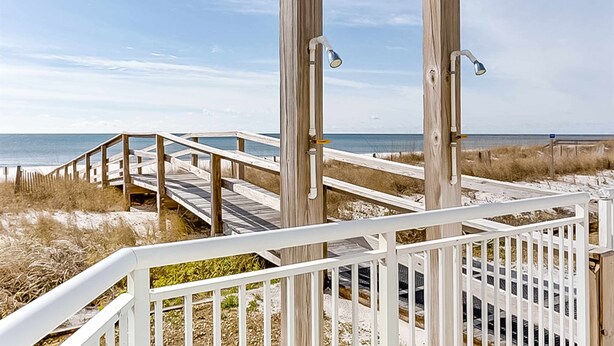 A wooden boardwalk leading to a beach with a clear view of the ocean.