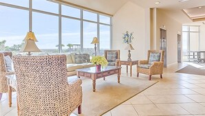 A spacious living room with large windows, wicker furniture, and a view of the outdoors.