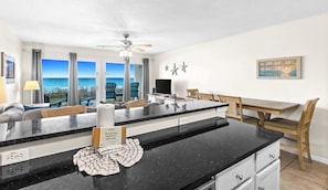 A kitchen with a large island, dining area, and a view of the ocean. - Oceanfront Condo w/ AC, WiFi, Shared Pool, & Seasonal Beach Service Rentals (Destin)
