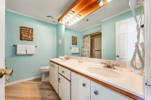 A bathroom with two sinks, a toilet, and a shower. There are towels hanging on the wall and a hairdryer on the counter. - Resort condo near beach with private balcony, WiFi, pool, tennis & dock (Panama City Beach)