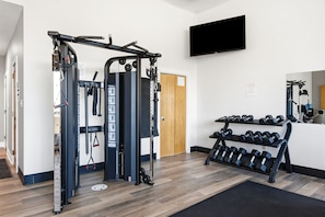 A gym with a pull-up bar, weight stack, and dumbbells. - Attractive home with spacious balcony, pool view & pickleball - near beach (Santa Rosa Beach)