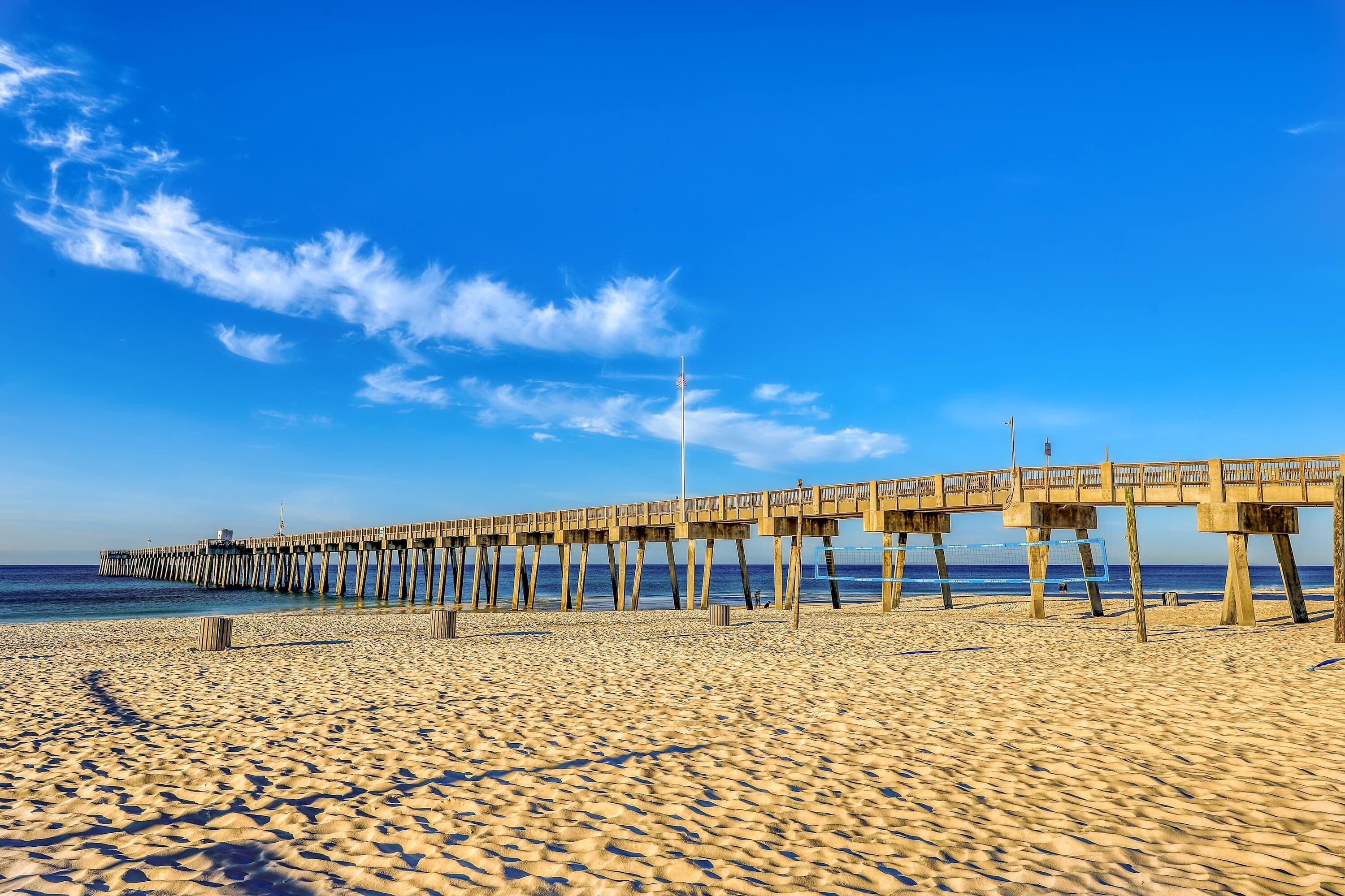 Een strand met een houten pier die zich uitstrekt in de oceaan.