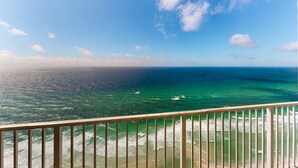Een balkon met uitzicht op de oceaan en een heldere lucht.