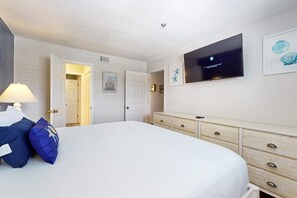 A bedroom with a bed, a dresser, a television, and a door leading to another room. - Upgraded Gulf Beachfront Condo with WiFi, Shared Pool, & Seasonal Beach Service (Destin)
