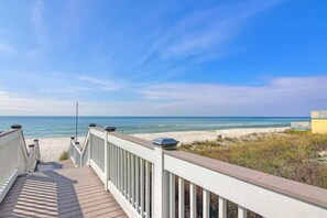 A wooden boardwalk leading to a beach with a clear view of the ocean and a building in the distance. - Beautiful condo located on the beach - close to attractions, pool & Hot tub (Panama City Beach)