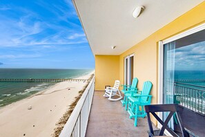 Un balcone con vista sulla spiaggia e sull'oceano. Si vedono sedie turchesi e una sedia nera.