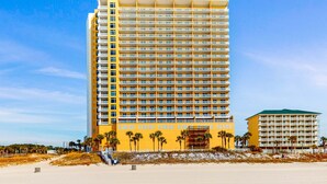 Un hotel alto con numerosi balconi e vista sulla spiaggia.