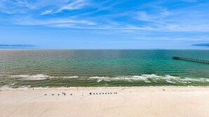 Una spiaggia con un molo che si estende nell'acqua, spiaggia sabbiosa e cielo sereno.