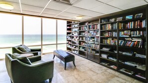 A library with bookshelves, a bench, and a view of the ocean. - 25th-floor ocean-view condo with pool, hot tub & fast WiFi (Panama City Beach)