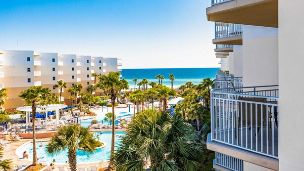 Ein Resort mit Poolbereich, Palmen und Meerblick.