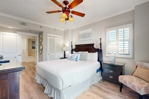 A bedroom with a large bed, a wooden nightstand, a dresser, a chair, a ceiling fan, and a window with blinds. - 3rd Floor Upscale, Welcoming Condo At Waterscape Waterfall, Lazy River (Fort Walton Beach)