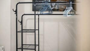 Een stapelbed met een metalen frame en planken, een kapstok aan de muur, en een schilderij van een leeuw.