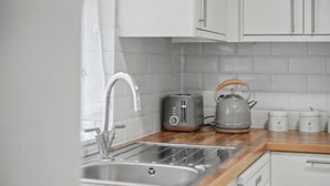Een keuken met een roestvrijstalen spoelbak, een broodrooster en een waterkoker op een houten aanrecht.
