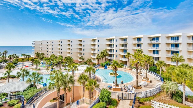 Un hôtel doté de nombreux balcons, d’une piscine et de palmiers.