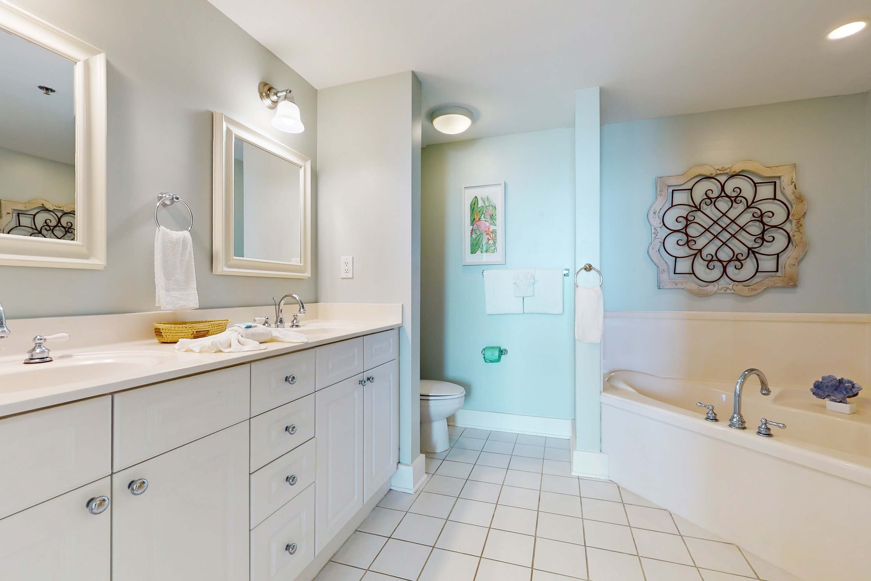 A bathroom with a white vanity, a bathtub, and a toilet.